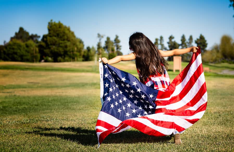 A girl holding an American flag in her home.